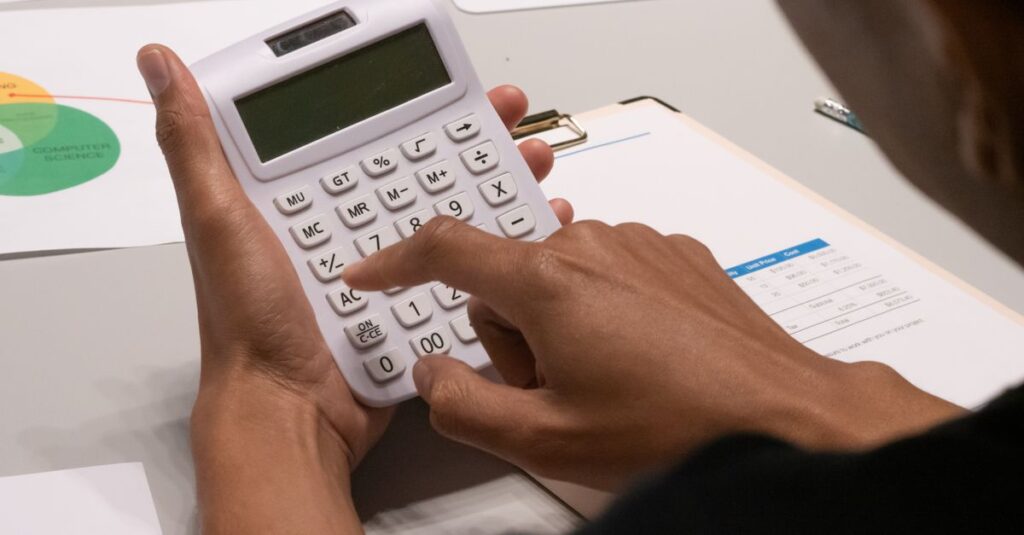 Maos usando calculadora sobre documentos financeiros em uma mesa de escritorio
