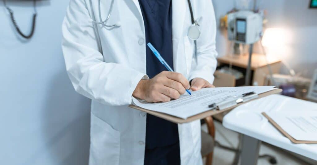 Médico de jaleco revisando anotações e documentos em ambiente clínico