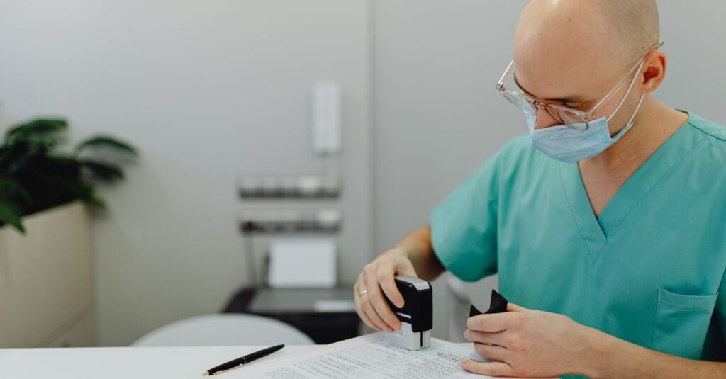 Médico de jaleco revisando documentos sobre a mesa de um consultório