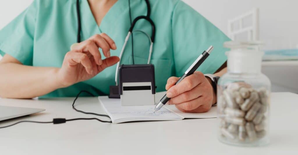 Médico preenchendo uma receita durante consulta sobre prescrição de medicamentos