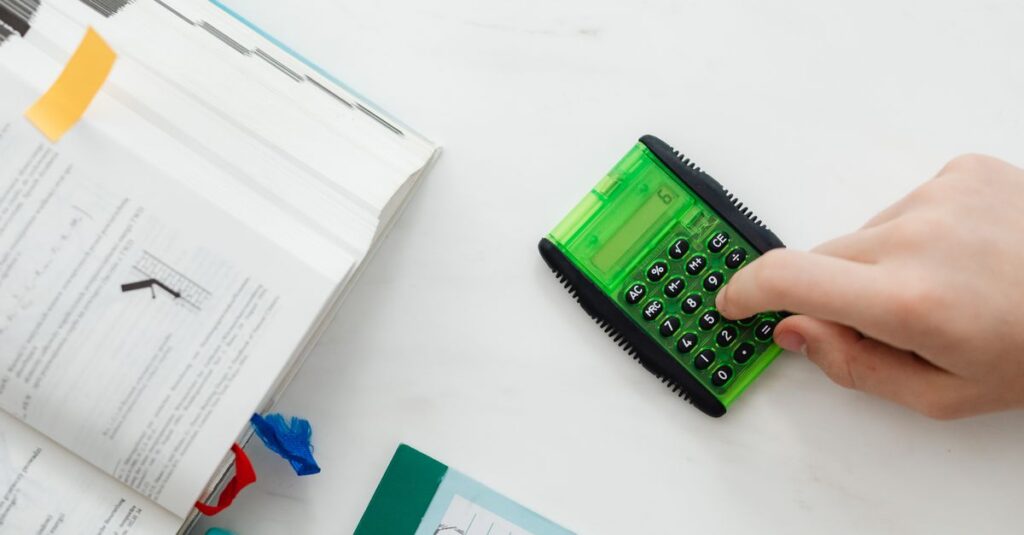 Médico calculando o saldo devedor do Fies com calculadora e documentos sobre a mesa