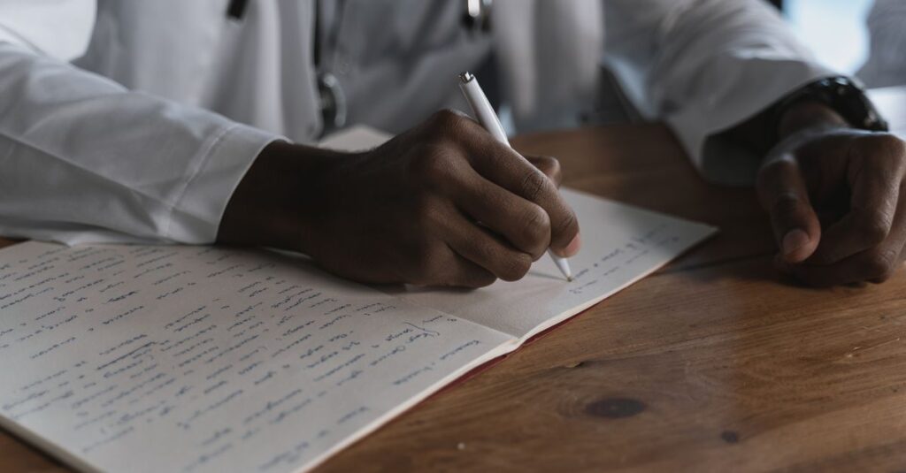 Médico registrando informações no prontuário médico com caneta