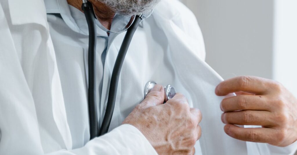 Médico de jaleco com estetoscópio analisando documentos no consultório