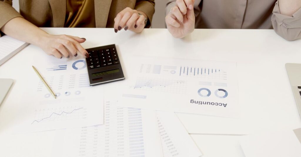 Mesa de escritório com planilhas e calculadora usadas no cálculo do Fator R do médico