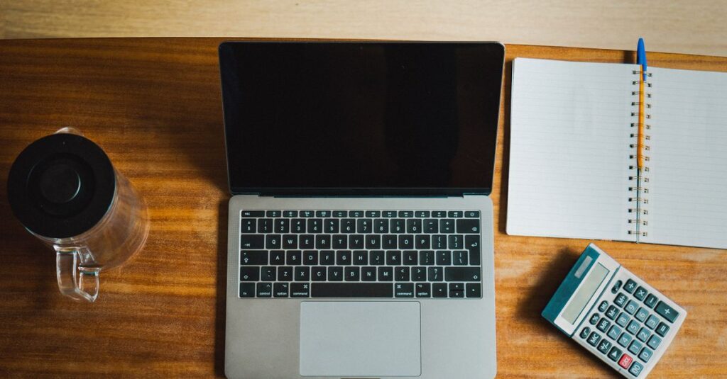 Calculadora, laptop e caderno sobre a mesa para renegociar a dívida do FIES do médico
