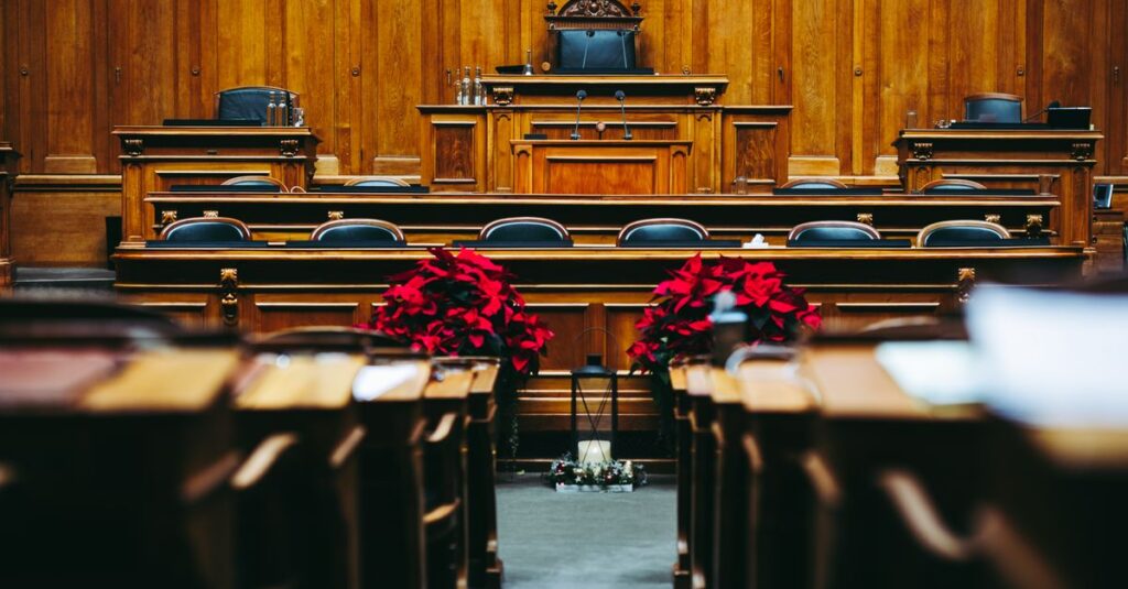 Sala de tribunal em madeira, vazia, representando o processo judicial que corre em paralelo ao processo ético do médico no CRM