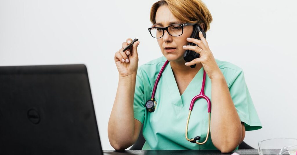 Médico usando o celular e o computador para divulgar o consultório
