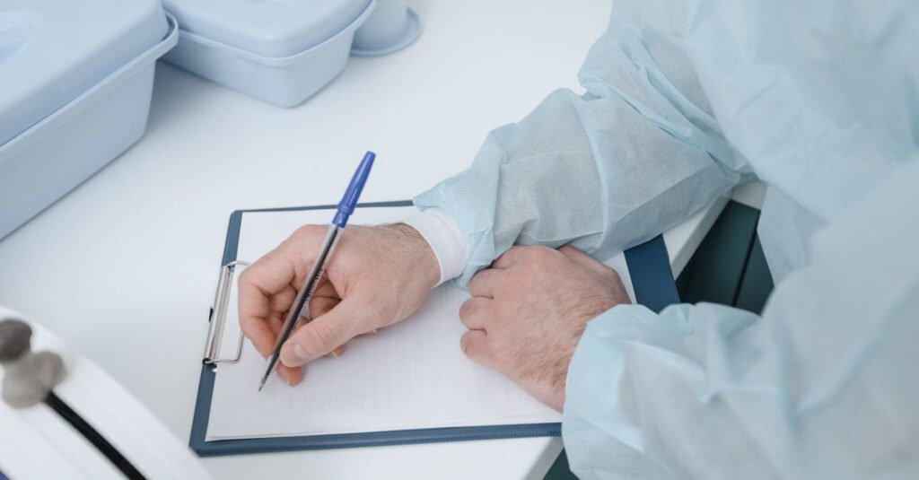 Médico preenchendo o prontuário em uma prancheta, registro usado como prova na defesa