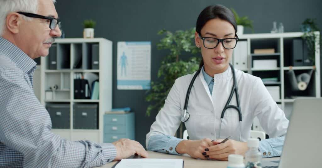 Médico conversando com paciente na mesa do consultório antes de um procedimento